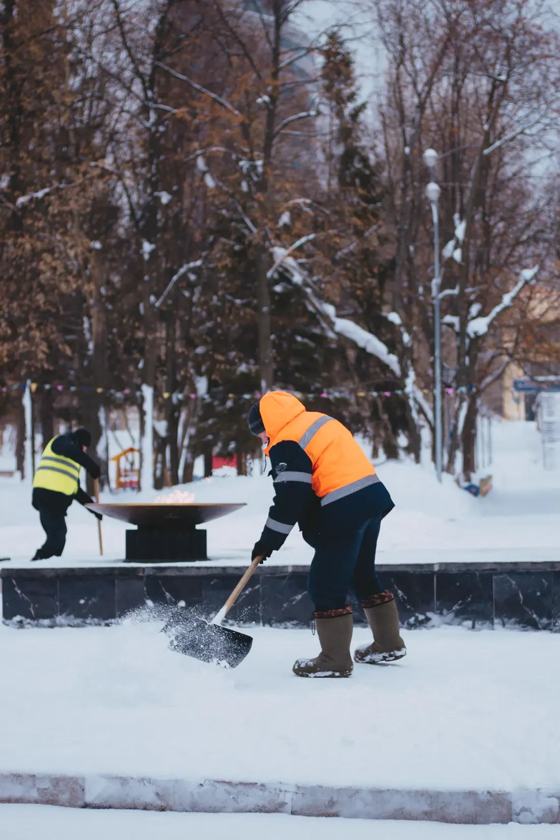 Workers in safety vests clearing snow